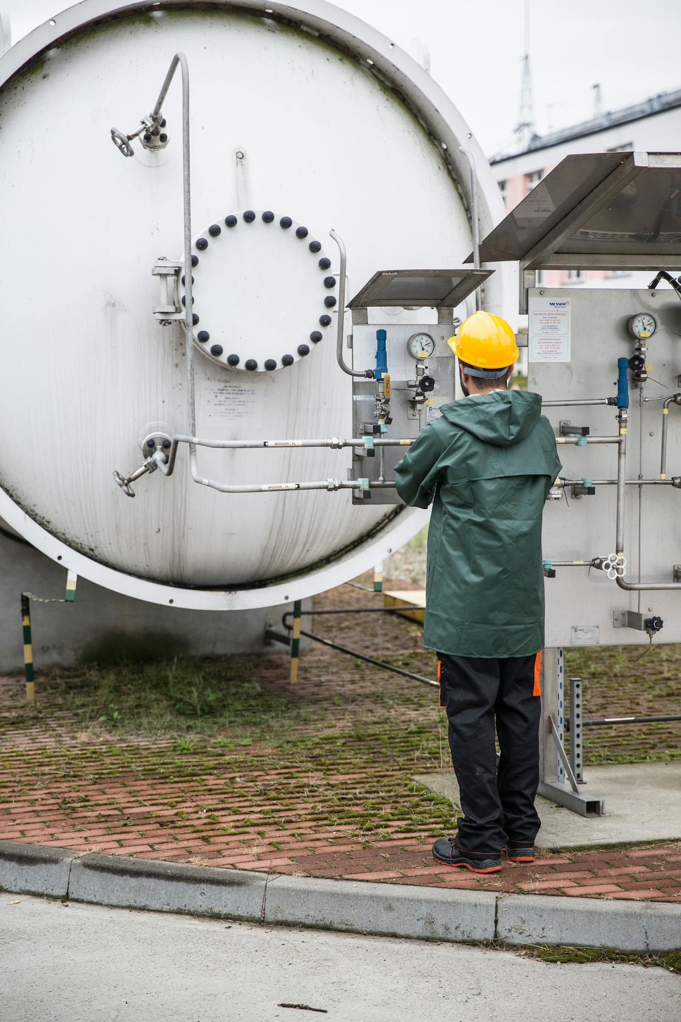 A worker in safety gear operates a large industrial machine outdoors, ensuring operational safety.